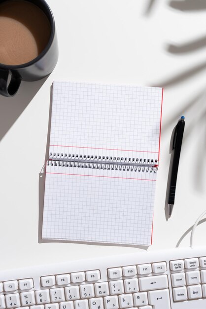 Caderno com mensagens importantes em ambos os lados na mesa com caneta de café e teclado Informações cruciais no bloco na mesa com copo e lápis Atualizações tardias apresentadas