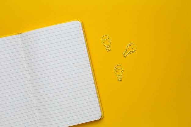 Caderno com páginas em branco e paperclip lâmpada idéia em amarelo