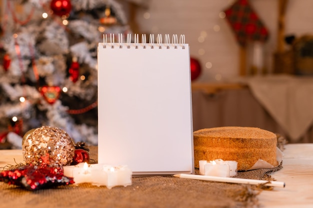 caderno com páginas vazias em uma mesa de madeira no fundo da cozinha de uma árvore de Natal. Ano Novo