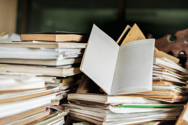 Caderno com pilha de velhos livros na mesa de madeira,