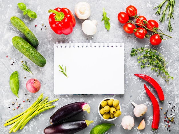 Caderno com vegetais e ervas em fundo de concreto cinza