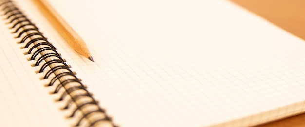 Foto caderno de close-up com um lápis em cima da mesa.