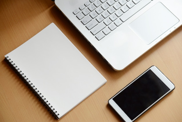 Foto caderno de computador com smartphone e notebook na madeira