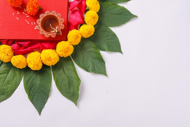 Foto caderno de contabilidade vermelho, diya e rangoli de flores em branco