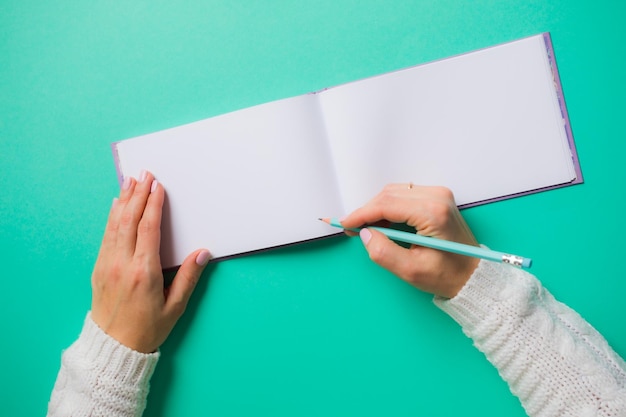 Caderno de desenho aberto com páginas em branco Mulher em branco segurando lápis se preparando para desenhar espaço de cópia de fundo turquesa claro