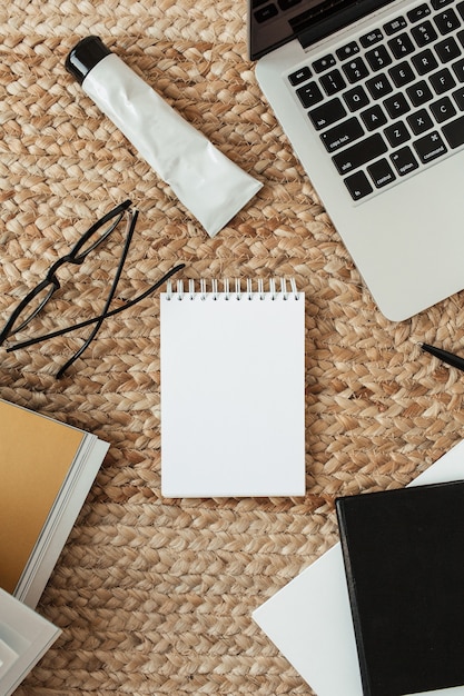 Caderno de folha em branco com espaço vazio da cópia, laptop, óculos. Camada plana, vista de cima, mesa de escritório em casa, área de trabalho