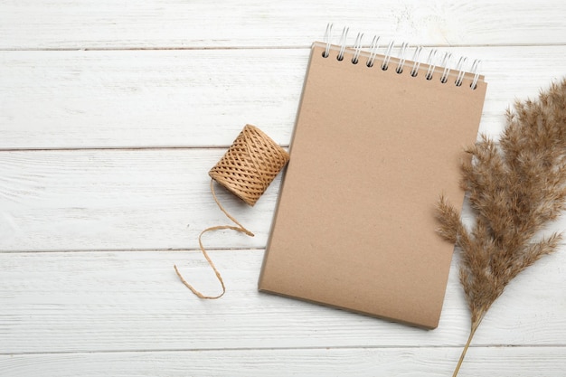 Caderno de Kraft elegante e elementos de decoração em mesa plana de madeira branca Espaço para texto