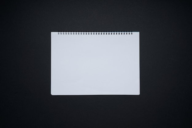 Caderno de notas branco em branco. Camada plana e vista superior com espaço de cópia em fundo preto.