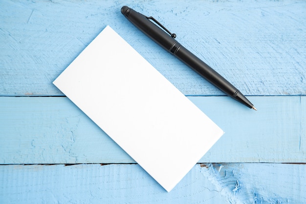 Caderno de papel e caneta preta em madeira azul