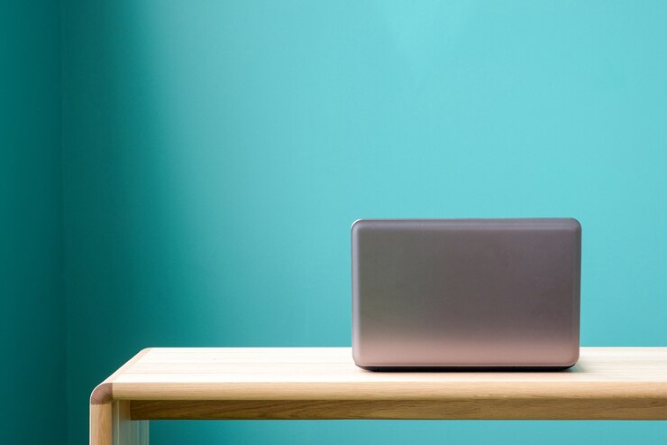 Foto caderno do computador, lap-top, na mesa do escritório sobre o fundo da parede verde, com espaço na cópia