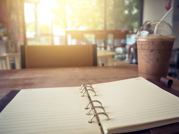 Foto caderno e café gelado no fundo de madeira