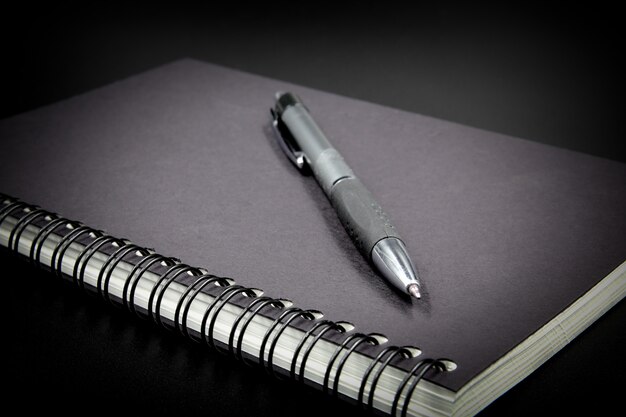 Caderno e caneta em fundo preto