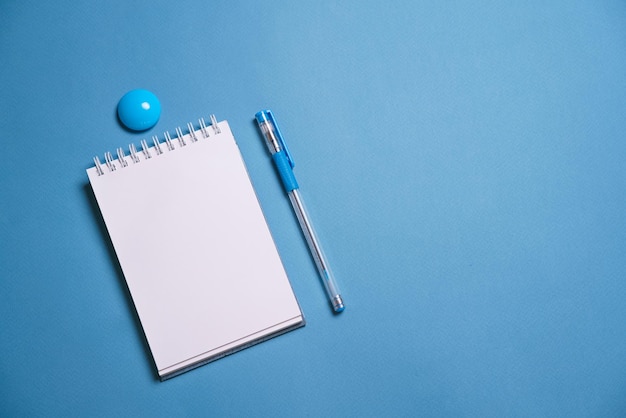 Caderno e caneta em um fundo azul Vista superior com espaço de cópia Artigos de papelaria