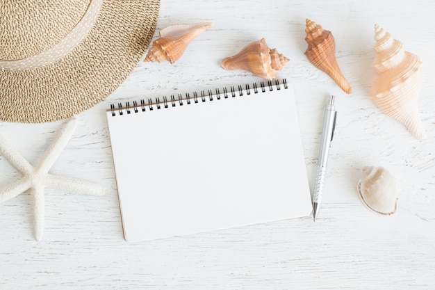 caderno e concha para as férias de verão em madeira branca