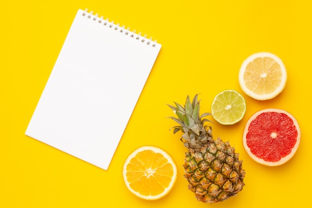 Caderno e frutas tropicais abacaxi, laranja e limão