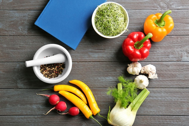 Caderno e legumes com especiarias na mesa da cozinha Conceito de aulas de culinária