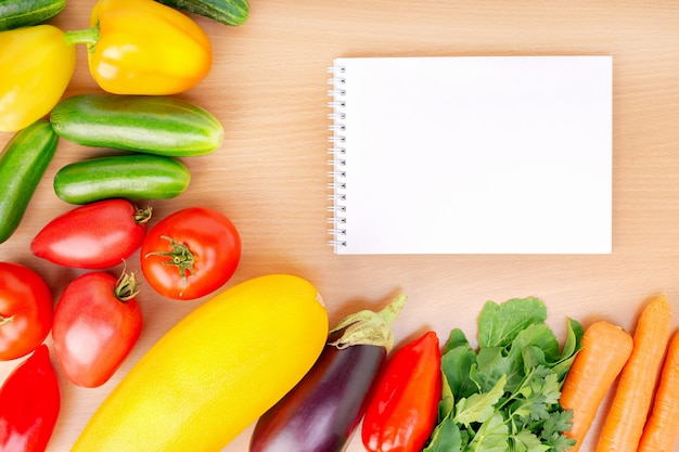 Caderno e legumes frescos na mesa.