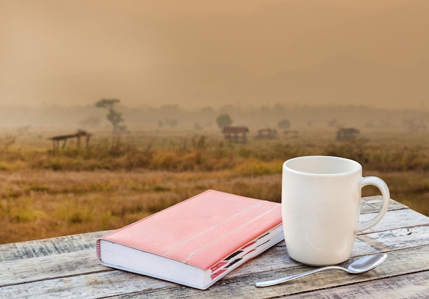 Caderno e xícara de café na mesa de madeira com desfoque de fundo