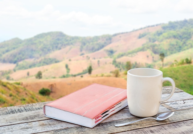 Caderno e xícara de café na mesa de madeira com desfoque de fundo