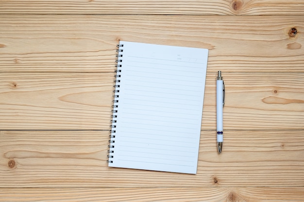 Caderno em branco com caneta em fundo de madeira.