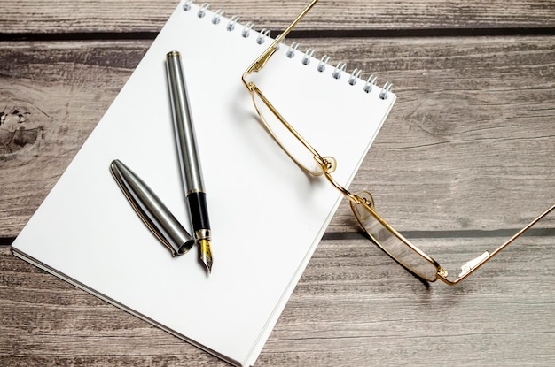 Caderno em branco com caneta está em cima da mesa de escritório branca vista superior com espaço de cópia