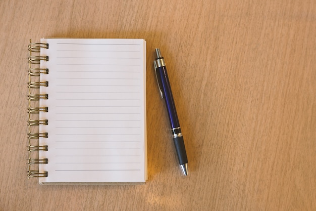 Caderno em branco com caneta na mesa de madeira