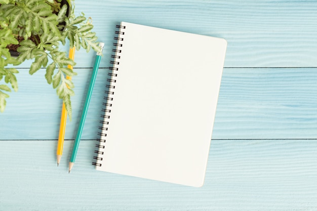 Caderno em branco com e lápis sobre fundo azul