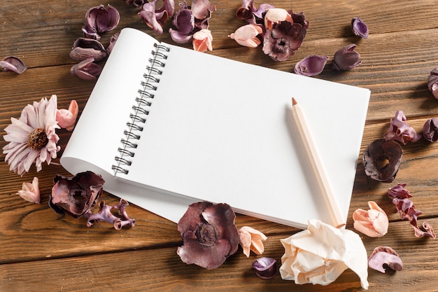 Caderno em branco com flores na mesa de madeira vintage