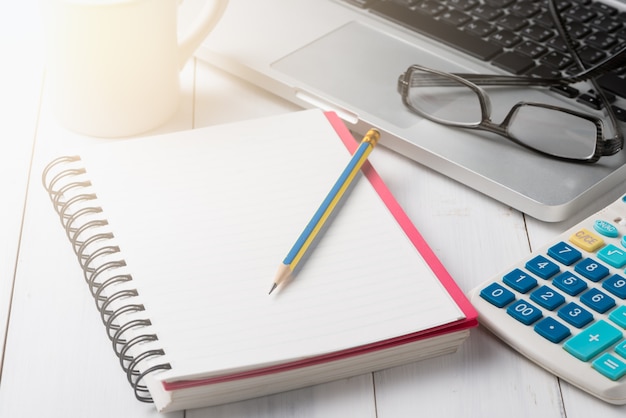 caderno em branco com lápis e laptop