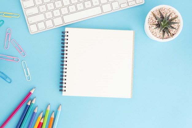 Caderno em branco com teclado e lápis azul