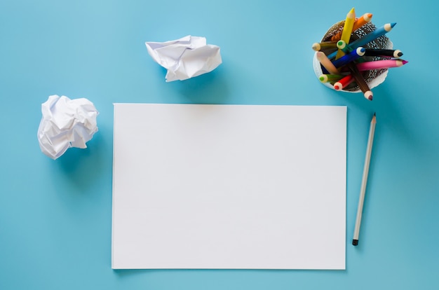 Caderno em branco, conjunto de lápis coloridos e papéis amassados. Fundo de papel.