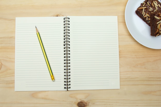 Caderno em branco e lápis na mesa de madeira