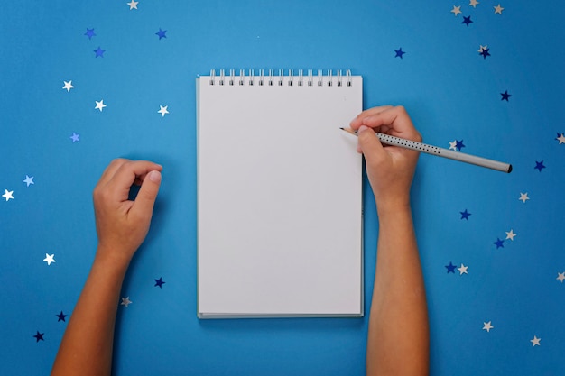 Caderno em branco e mãos femininas com lápis