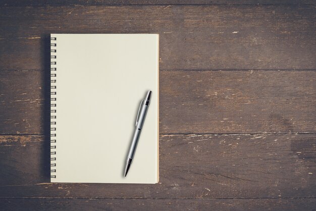 Caderno em branco e mesa de madeira com espaço.