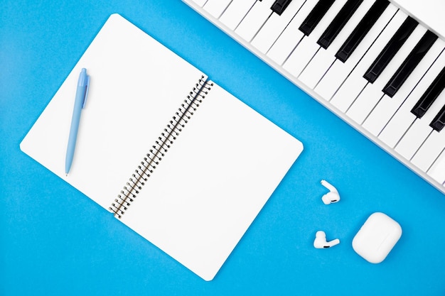 Caderno em branco e piano no conceito de visão superior de fundo azul de criatividade musical e educação sintetizador branco plano