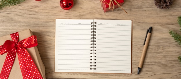 Caderno em branco, presente de Natal e caneta na mesa de madeira, vista superior e espaço de cópia. Natal, Feliz Ano Novo, Metas, Resolução, Lista de Tarefas, Conceito de Estratégia e Plano