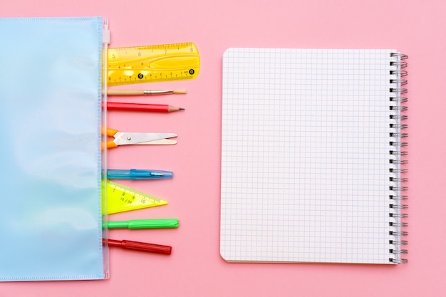 Caderno escolar e vários materiais de escritório de volta ao conceito de escola em fundo rosa brilhante