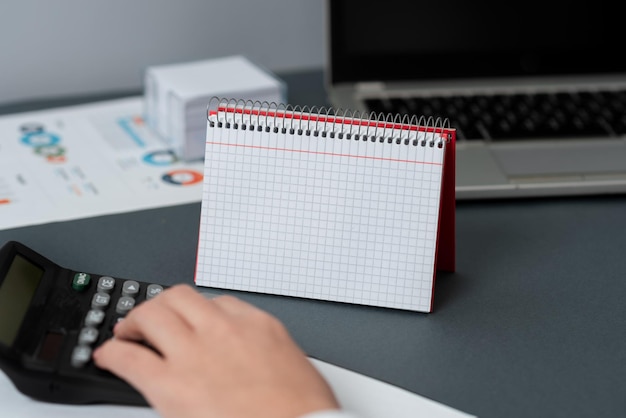 Foto caderno espiral aberto em branco com uma calculadora e uma caneta colocada sobre uma mesa bloco de notas forrado vazio e lápis em cima de uma mesa com um dispositivo de cálculo