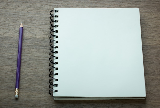 Caderno espiral em branco e lápis em fundo de madeira escura