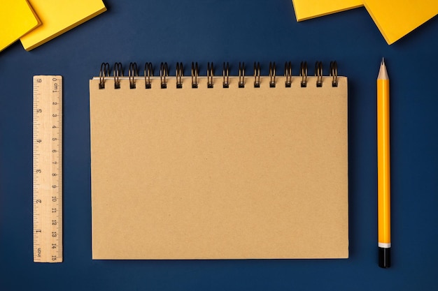 Caderno marrom vista superior com lápis amarelo e bloco de notas na mesa de trabalho azul marinho