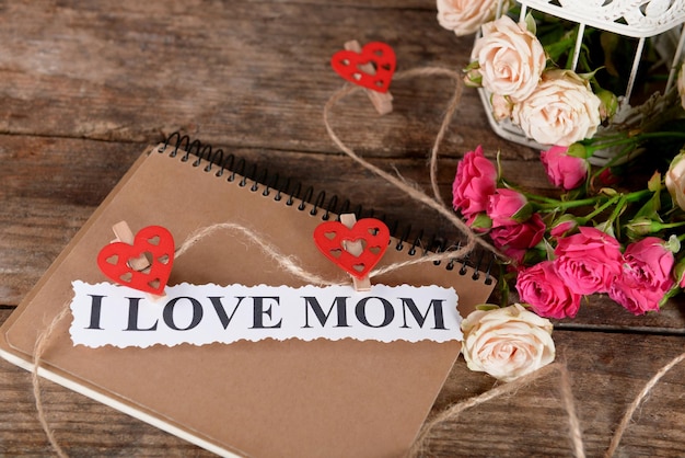 Caderno para o dia das mães e flores em fundo de madeira