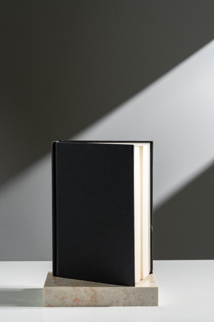 Foto caderno preto à luz do sol contra fundo cinzento