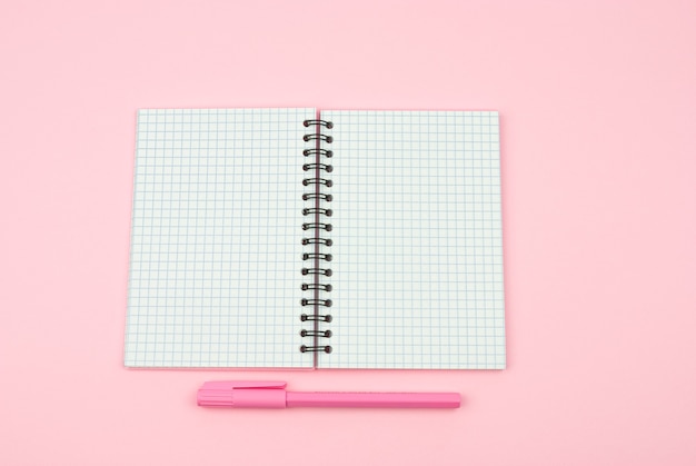Caderno rosa e caneta rosa em um fundo rosa
