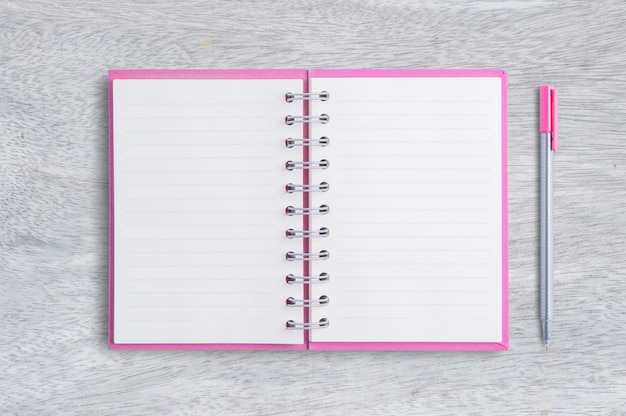 Foto caderno rosa em branco e caneta em madeira fundo