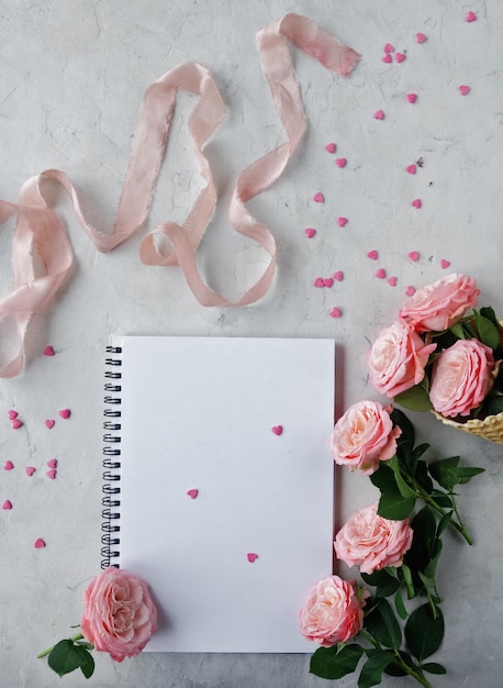 Caderno rosas fita rosa e doces doces em forma de coração em fundo branco decoração para dia dos namorados ou cartão de dia do casamento vista superior plana lay foco seletivo