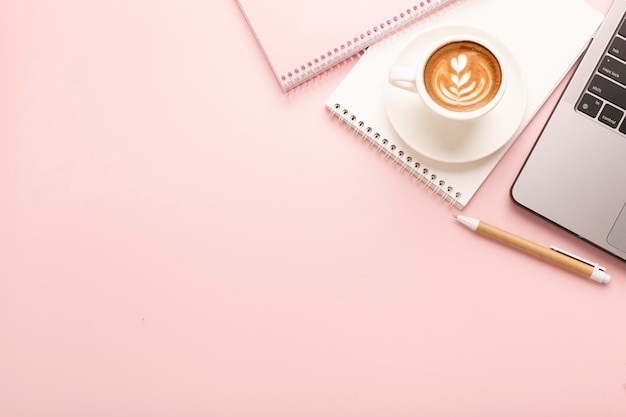 Caderno uma xícara de café com um belo padrão e um bloco de notas em um fundo rosa Lugar para texto