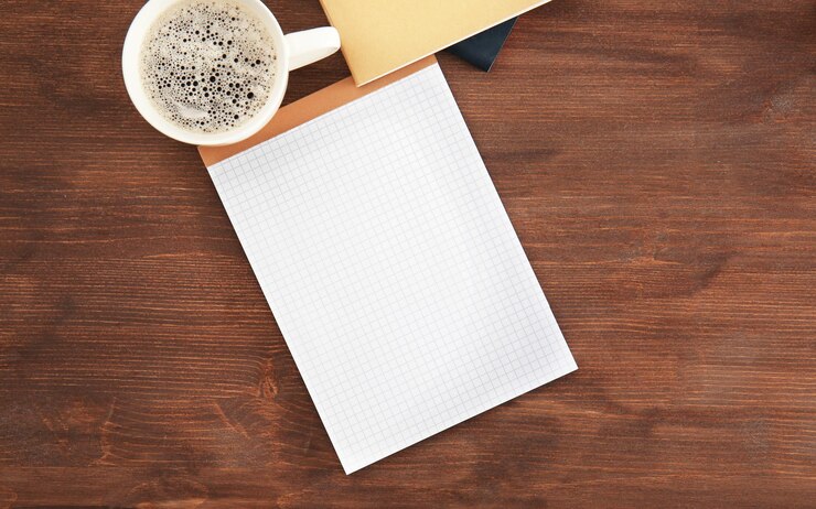 Foto caderno vazio com uma chávena de café na mesa conceito de entrevista de emprego