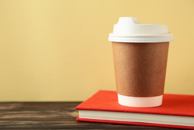 Caderno vermelho com xícara de café em fundo bege Conceito de educação empresarial com espaço de cópia