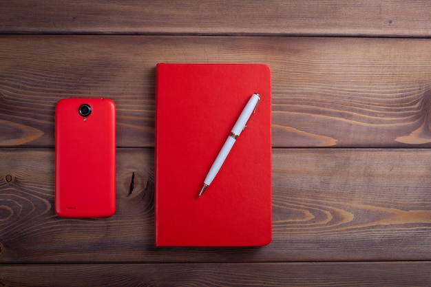 Caderno vermelho e um smartphone.