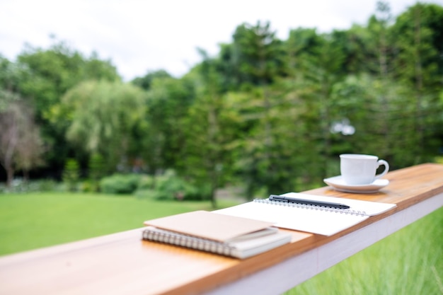 Cadernos de livros e xícara de café na mesa de madeira ao ar livre